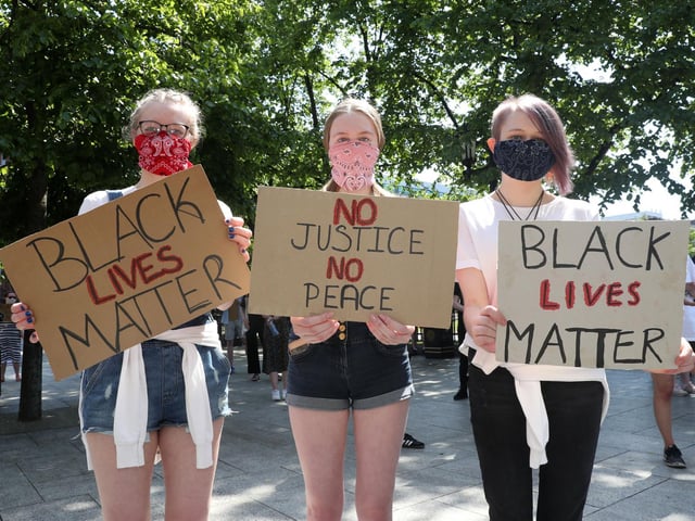 Three young women hold their placards aloft at the rally in Belfast.