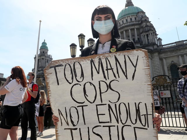 'Too many cops, not enough justice' reads a placard at the solidarity rally in Belfast on Monday.