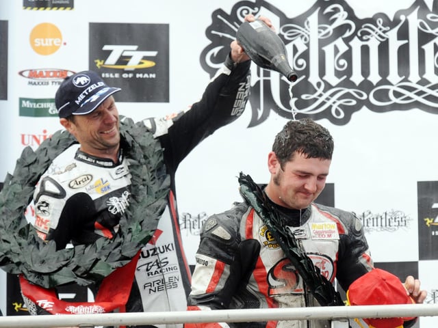 Runner-up Bruce Anstey soaks race winner Michael Dunlop with champagne on the TT rostrum.