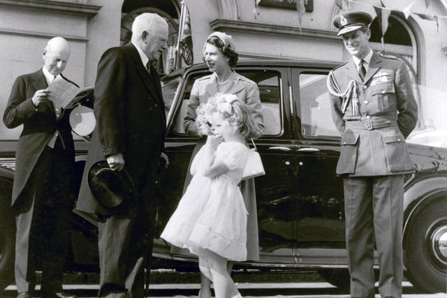 A candid moment: H.R.H Prince Philip smiles at the shy, three-year old Anne Irwin, who has just presented flowers to H.R.H. Queen Elizabeth II outside the Assembly Rooms (this building), in 1953 during her coronation tour. The sovereign is chatting with L.U.D.C. chairman, A.N. Stevenson.