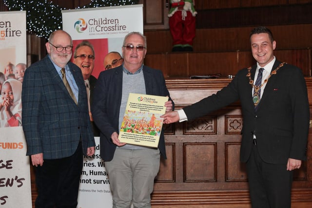 Richard Moore (Children in Crossfire) presents a gift to Mayor Graham Warke at an event to mark the 25th anniversary of Children in Crossfire, held in the Guildhall.  Included is Marcus O'Neill, chairperson, Children in Crossfire. (Photo - Tom Heaney, nwpresspics)