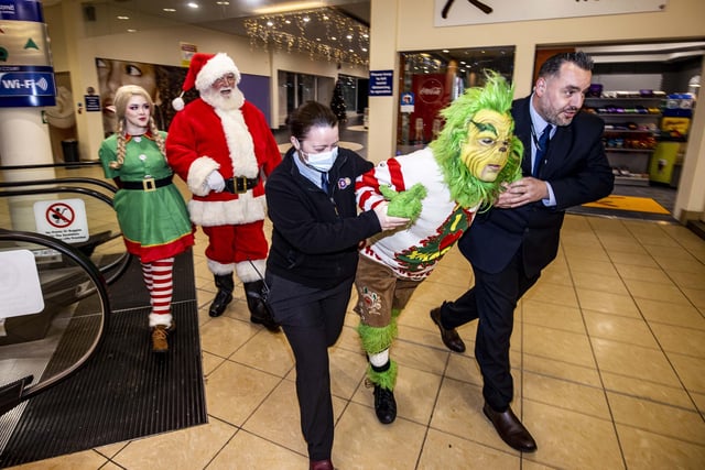 Security from the Diamond Centre in Coleraine remove the Grinch for having no Christmas spirit as Santa and an elf look on
