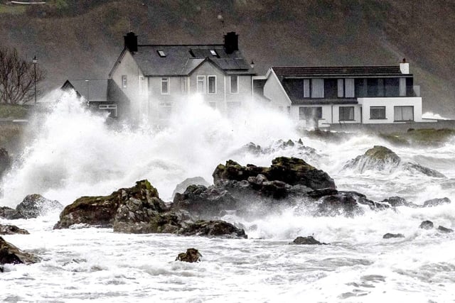 The choppy sea breaks over houses at Cushendall in Co Antrim.