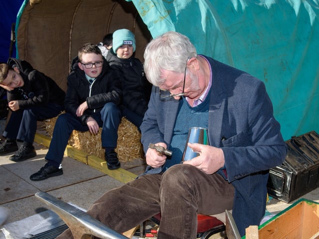 Longtower PS kids look on as tinsmith Tom McDonald at the Traveller Living History Exhibition which visited Guildhall Square this week.