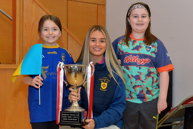 Pupils Grace Callan and Amelia Doherty, P5 pupils at St Patrick’s Primary School Pennyburn, pictured with Steelstown Brian Og’s ladies player Ella-Rose Sainsbury and the Derry Ladies Senior Championship trophy during a visit to the school on Friday morning last. Photo: George Sweeney.  DER2208GS – 081