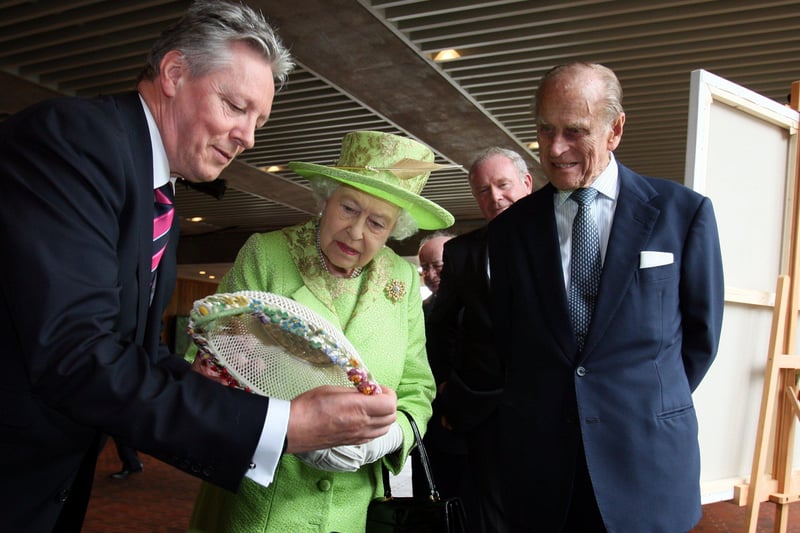 Queen Elizabeth II and Prince Philip,Duke of Edinburgh admire a gift held by Northern Ireland First Minister Peter Robinson and watched by Deputy First Minister Martin McGuinness during a visit to the Lyric Theatre on June 27, 2012 in Belfast, Northern Ireland.
