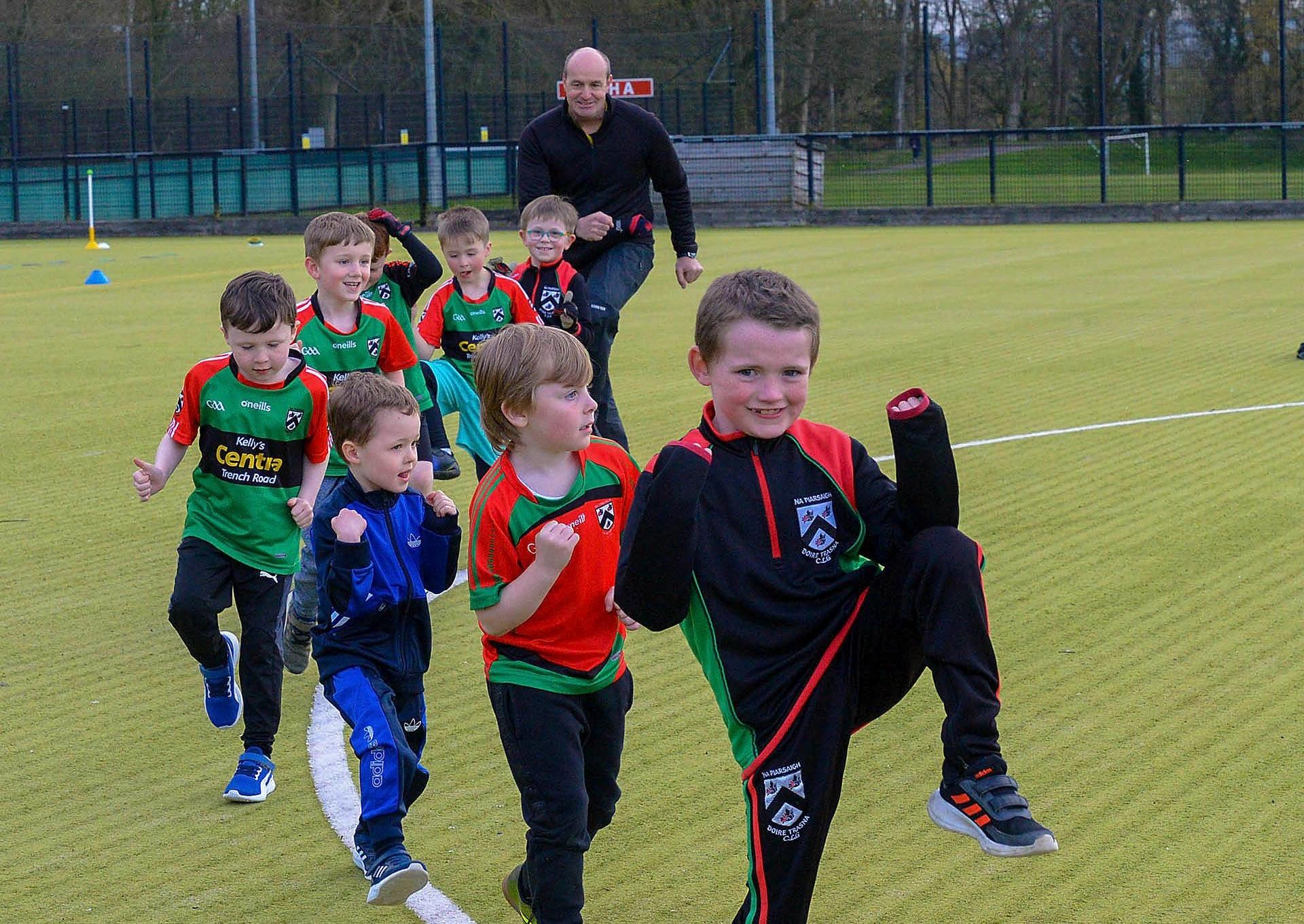 Paul Simpson, Doire Trasna coach, and nursery footballers getting some stretching exercise during a training session at the Foyle Arena recently. Photos: George Sweeney. DER2115GS – 068