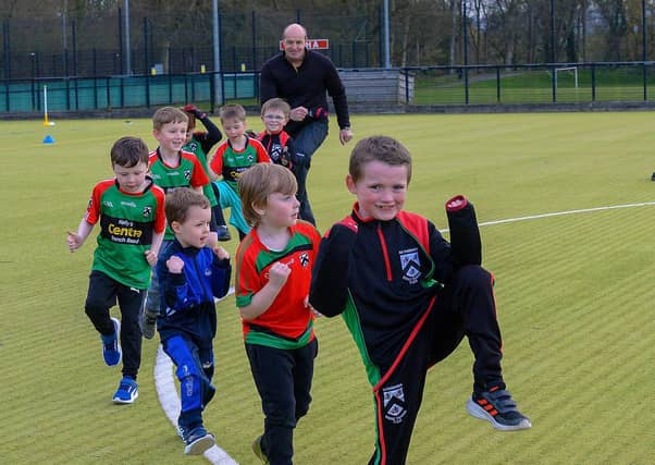 Paul Simpson, Doire Trasna coach, and nursery footballers getting some stretching exercise during a training session at the Foyle Arena recently. Photos: George Sweeney. DER2115GS – 068
