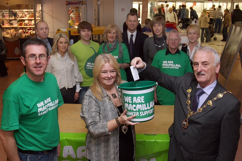 The Mayor of Londonderry Alderman Drew Thompson, accompanied by the Mayoress Linda Watson, drawing the winning ticket in the Macmillan Cancer Support Grand Christmas raffle at The Richmond Centre. Included are Paul Sweeney (left), area fund raiser for Macmillan, local volunteers and representatives from the Richmond Centre traders. LS51-513MT.