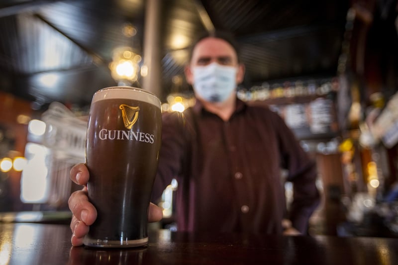 Staff member at The Garrick Bar in Belfast holds a poured pint of Guinness after the latest easing of the Covid-19 rules in Northern Ireland