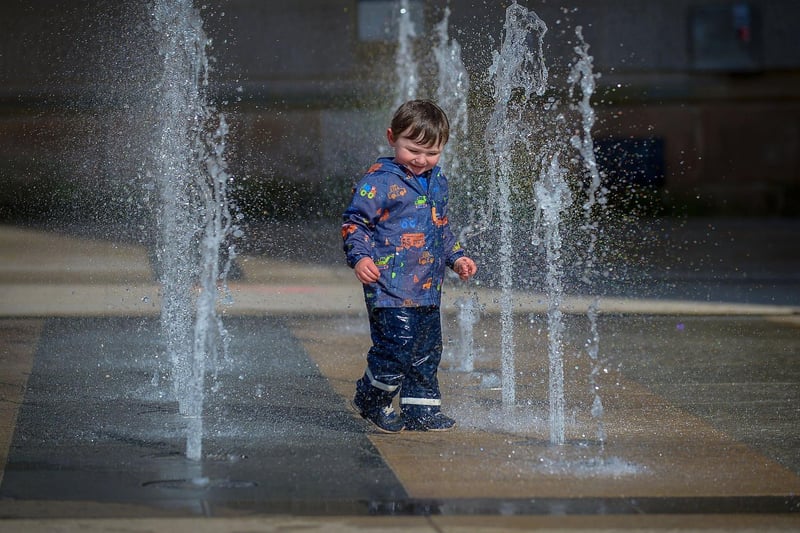 Dahir McBrien, aged 2, has fun in the water fountains, in Guildhall Square, during the Bank Holiday weekend. Photo: George Sweeney / Derry Journal.  DER2117GS - 056