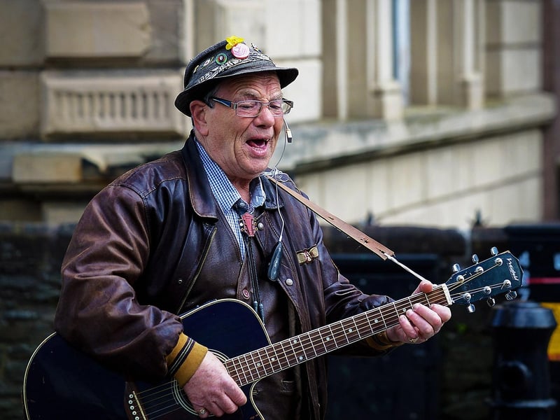A busker plays in the city centre busy with shoppers. DER2119GS – 006