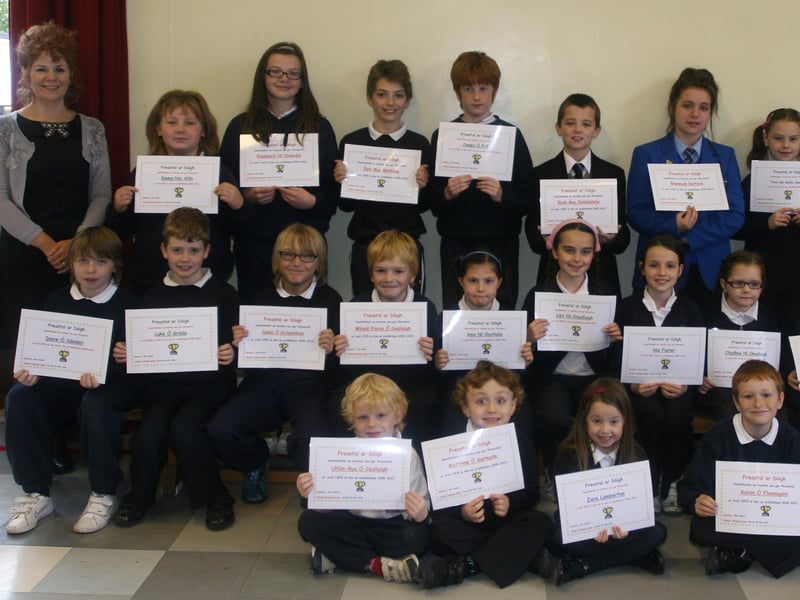 Pupils, past and present, from Bunscoil Cholmcille, Steelstown who received certificates of attendance at the school on Thursday morning. On left is Aine Hudson, Education Welfare Officer, who presented the awards and, on right, Caroline Mhic Colla, teacher. 1510JM33