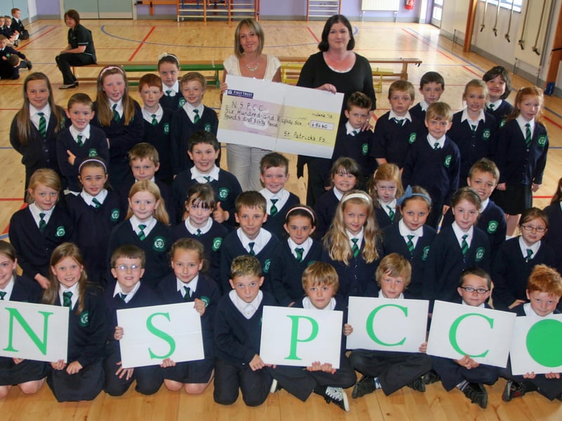 Pupils from St. Patrick's PS, Pennyburn P4 Year Group pictured during the presentation of a cheque to the NSPCC for £686, proceeds of donations from their First Communion monies. Presenting the cheque to Amy Gregg (NSPCC) is Karen Crumley, charities co-ordinator, St. Patrick's PS. 2506JM26