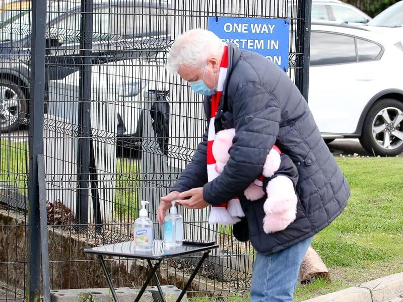 This fan is ensuring appropriate hygiene measures are taken as he applies hand gel before entering the ground.