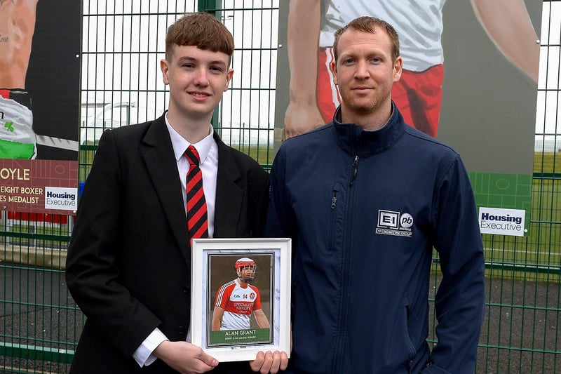 Tiarnan Quigley, St Brigid’s College, presents Na Magha’s Alan Grant with a photograph of Alan’s sporting hero mural on display at the Leafair Well-Being Village. DER2125GS - 025