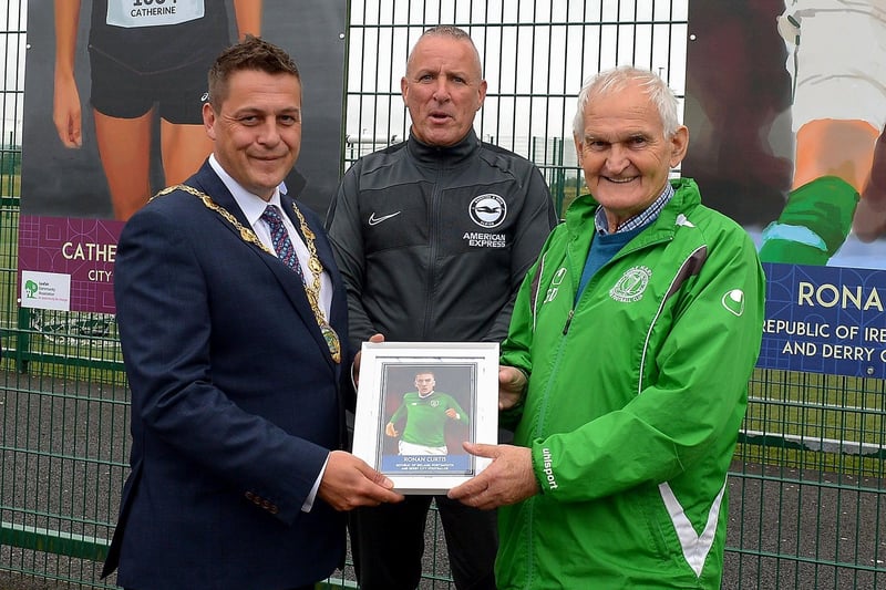 Mayor of Derry and Strabane Alderman Graham Warke and Leroy McCourt present Gerry Doherty with a photograph of the Ronan Curtis sporting hero mural on display at the Leafair Well-Being Village.  DER2125GS - 021