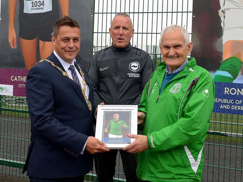 Mayor of Derry and Strabane Alderman Graham Warke and Leroy McCourt present Gerry Doherty with a photograph of the Ronan Curtis sporting hero mural on display at the Leafair Well-Being Village. DER2125GS - 021