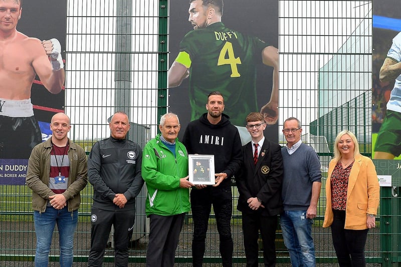 Gerry Doherty presents Shane Duffy with a photograph of Shane’s sporting hero mural on display at the Leafair Well-Being Village. Included in the photograph are John Ferry, NIHE, Leroy McCourt, Oisin McCartney , Eddie Breslin, NIHE, project sponsor and Karen Mullan MLA. Photos: George Sweeney / Derry Journal DER2125GS - 022