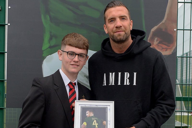 Oisin McCartney, St Brigid’s College, presents Shane Duffy with a photograph of Shane’s sporting hero mural on display at the Leafair Well-Being Village. DER2125GS - 024