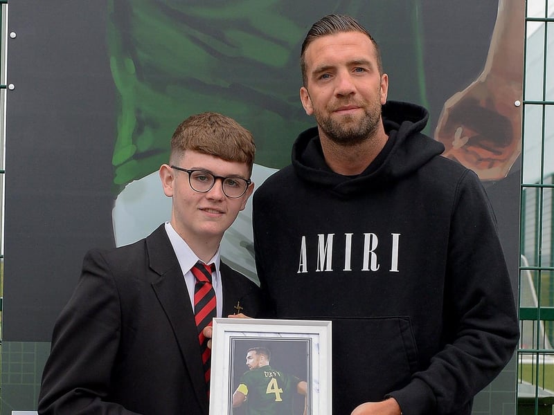 Oisin McCartney, St Brigid’s College, presents Shane Duffy with a photograph of Shane’s sporting hero mural on display at the Leafair Well-Being Village. DER2125GS - 024