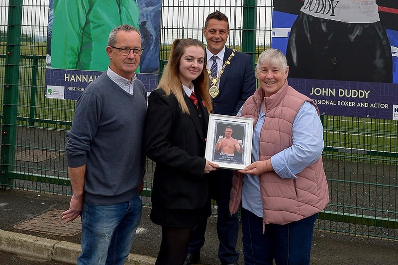 Carmel Chrystal receives a photograph of her son John Duddy’s sporting hero mural on display at the Leafair Well-Being Village from St Brigid's College pupil Louise Conlon. Included in the photograph are Eddie Breslin NIHE, project sponsors, and the Mayor of Derry and Strabane Alderman Graham Warke.  DER2125GS - 018