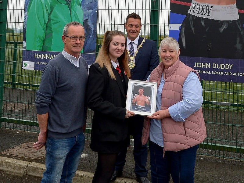 Carmel Chrystal receives a photograph of her son John Duddy’s sporting hero mural on display at the Leafair Well-Being Village from St Brigid's College pupil Louise Conlon. Included in the photograph are Eddie Breslin NIHE, project sponsors, and the Mayor of Derry and Strabane Alderman Graham Warke. DER2125GS - 018
