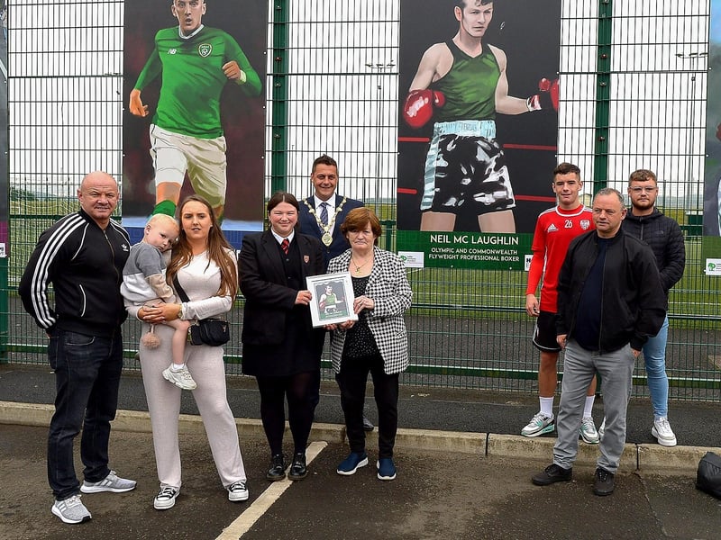 Margo McLaughlin and family receive a photograph of the Neil McLaughlin sporting hero mural on display at the Leafair Well-Being Village from St Brigid's College pupil Jorja O’Kane. Included in the photograph is the Mayor of Derry and Strabane Alderman Graham Warke. Photos: George Sweeney / Derry Journal DER2125GS - 020