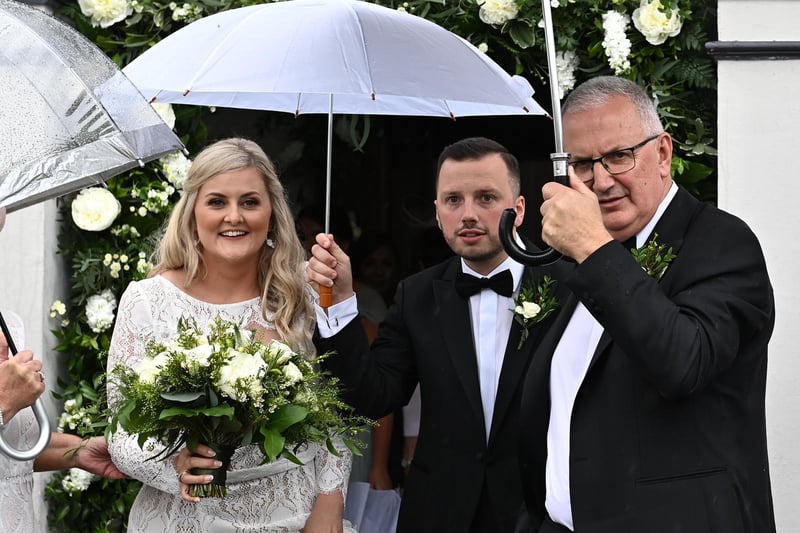 UUP Chair, Danny Kennedy, holds up an umbrella keeping son, Philip and his wife, Laura dry.