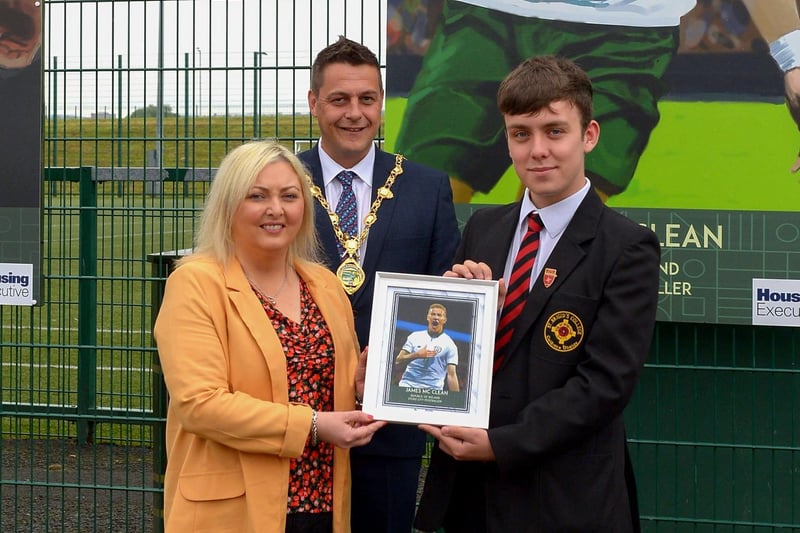 On behalf of James McClean, Karen Mullan MLA receives a photograph of the James McClean’s sporting hero mural on display at the Leafair Well-Being Village from St Brigid's College pupil Emmett McCallion. Included in the photograph is the Mayor of Derry and Strabane Alderman Graham Warke.  DER2125GS - 017