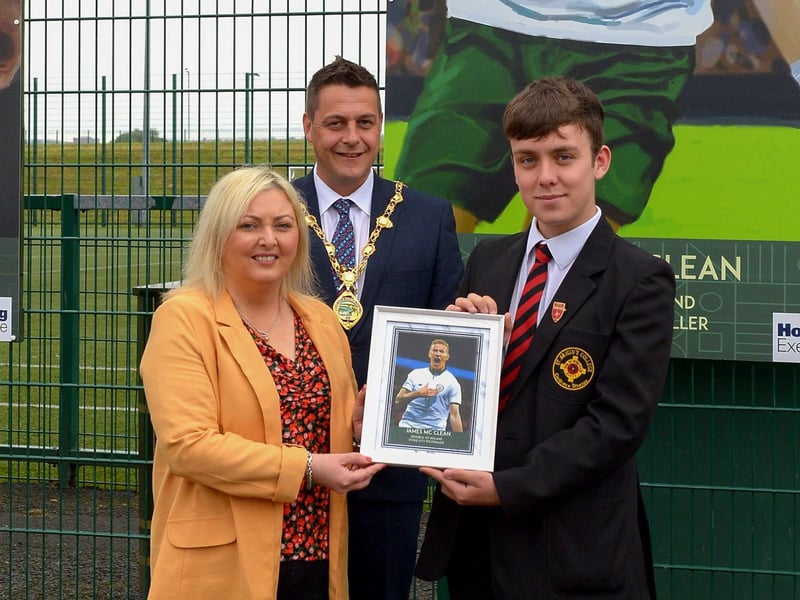 On behalf of James McClean, Karen Mullan MLA receives a photograph of the James McClean’s sporting hero mural on display at the Leafair Well-Being Village from St Brigid's College pupil Emmett McCallion. Included in the photograph is the Mayor of Derry and Strabane Alderman Graham Warke. DER2125GS - 017