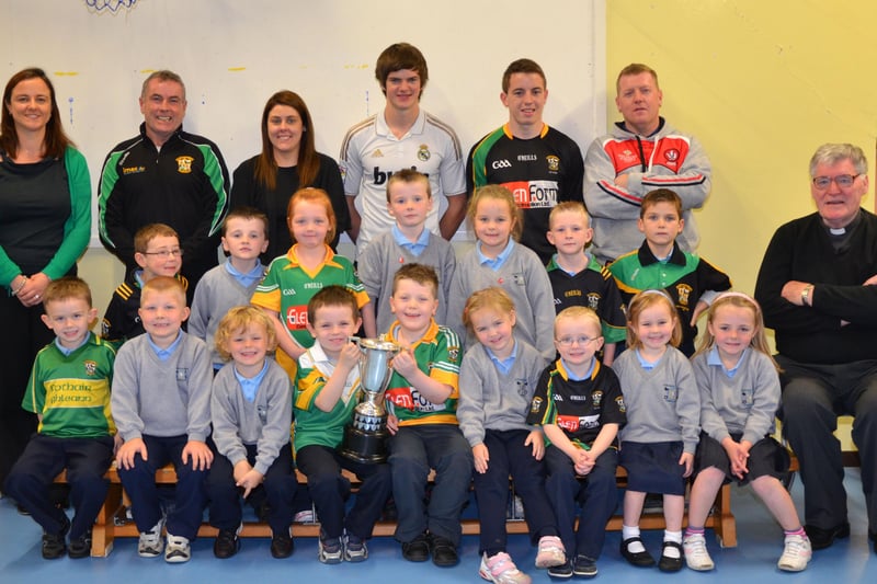 O'Brien's Foreglen club chairman Noel McFeely and senior players Eoighan Duffy and Eunan McFeely, with backroom management member Damien O'Connor pictured with the Intermediate Championship Trophy proudly displayed by the  P1/P3 pupils at St. Peter's and St. Paul's Primary School, Foreglen on Friday morning. Also pictured is their class teacher, Mrs. Fiona McCann (Principal) and Rev. Fr. Art O'Reilly. DER4313JM001