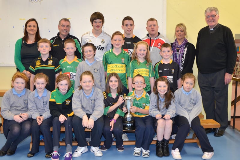 O'Brien's Foreglen club chairman Noel McFeely and senior players Eoighan Duffy and Eunan McFeely, with backroom management member Damien O'Connor pictured with the Intermediate Championship Trophy proudly displayed by the  P6/P7 pupils at St. Peter's and St. Paul's Primary School, Foreglen on Friday morning. Also pictured is their class teacher, Mrs. Fiona McCann (Principal) and Rev. Fr. Art O'Reilly. DER4313JM003