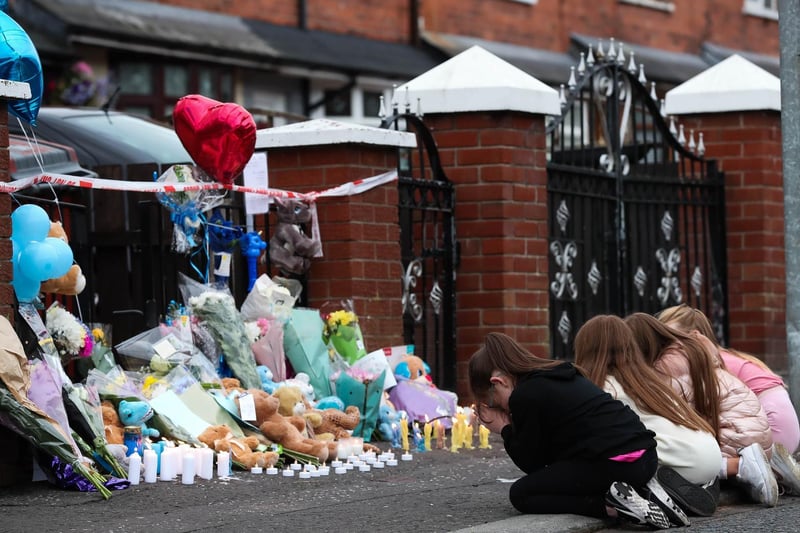 Four young girls pray on the footpath outside the house where little baby Liam O'Keefe was killed.