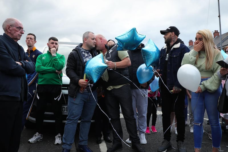 The father of baby Liam O'Keefe (black bodywarmer and yellow checked short-sleeved shirt) is embraced during the vigil.
