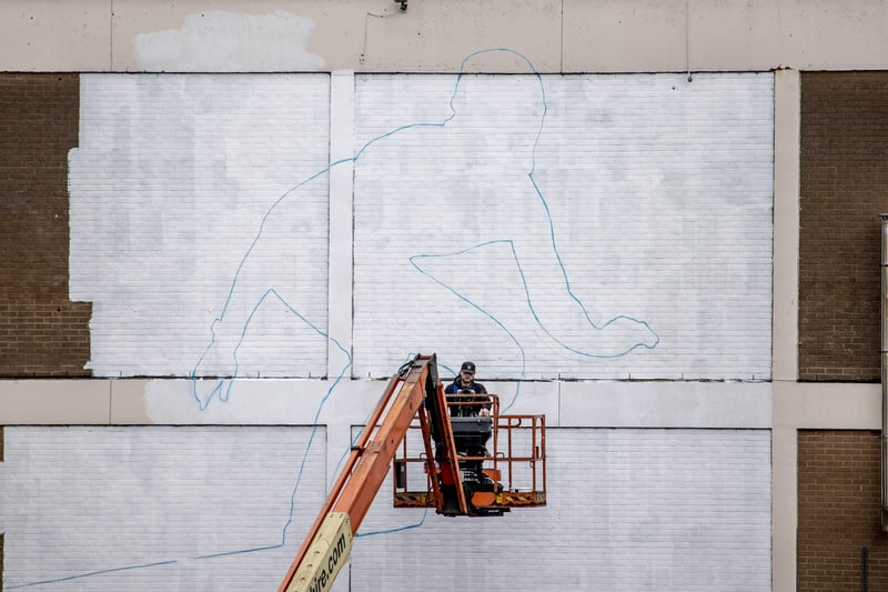 A mural of a surfer by artist Aches starts to take shape on a wall overlooking East Strand in Portrush as part of a wider scheme to increase the vibrancy of our town centres