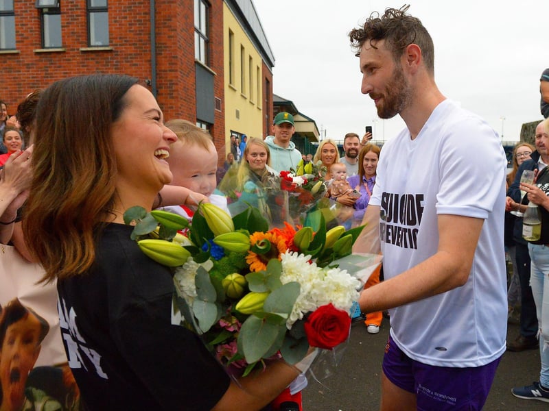 Sporting hero Danny Quigley presents his partner Emear with flowers on his arrival at Destined after completing a gruelling 10 Ironman Triathlons in 10 days in memory of his dad and fundraising over 74,000 for charities. Photo: George Sweeney / Derry Journal. DER2135GS – 026