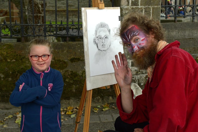 Molly, aged 5, poses with artist Sir Nirdosh who sketched her portrait during the Carnival of Colours festival last weekend. Photo: George Sweeney / Derry Journal.  DER2136GS – 013