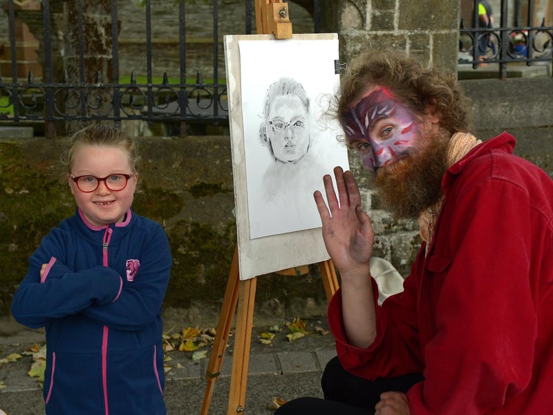 Molly, aged 5, poses with artist Sir Nirdosh who sketched her portrait during the Carnival of Colours festival last weekend. Photo: George Sweeney / Derry Journal. DER2136GS – 013