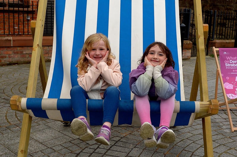 Faye, aged 5, and Macie (6) pose on a huge deck chair, in the Cathedral Quarter, during the Carnival of Colours festival last weekend. Photo: George Sweeney / Derry Journal.  DER2136GS – 012