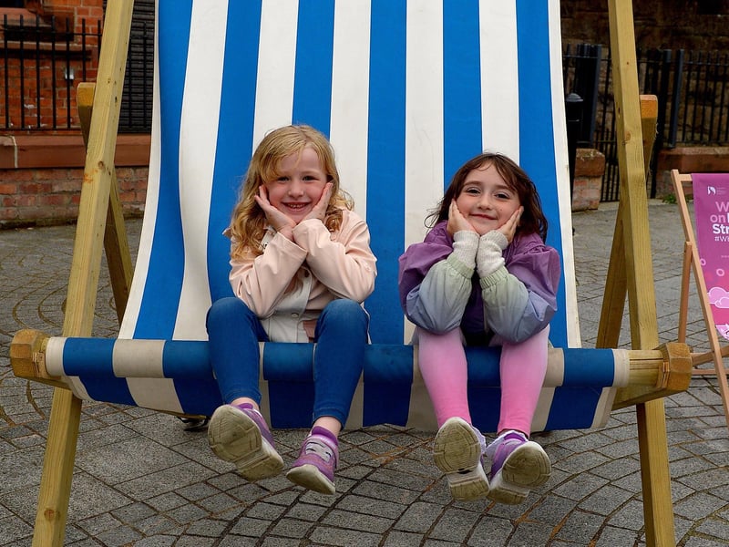 Faye, aged 5, and Macie (6) pose on a huge deck chair, in the Cathedral Quarter, during the Carnival of Colours festival last weekend. Photo: George Sweeney / Derry Journal. DER2136GS – 012