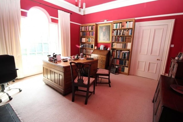 The study features an original marble and cast fireplace, solid oak bookshelves and an arched picture window that overlooks the front of the property, boasting amazing views of the land surrounding the house