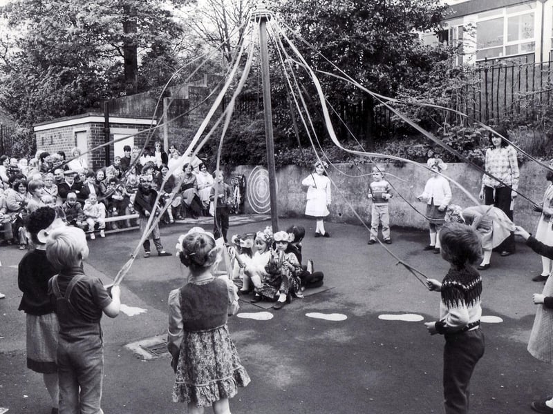 Children of Hucklow First School, Firth Park, Sheffield, dancing round the maypole before an audience of parents in the school yard, May 18, 1983