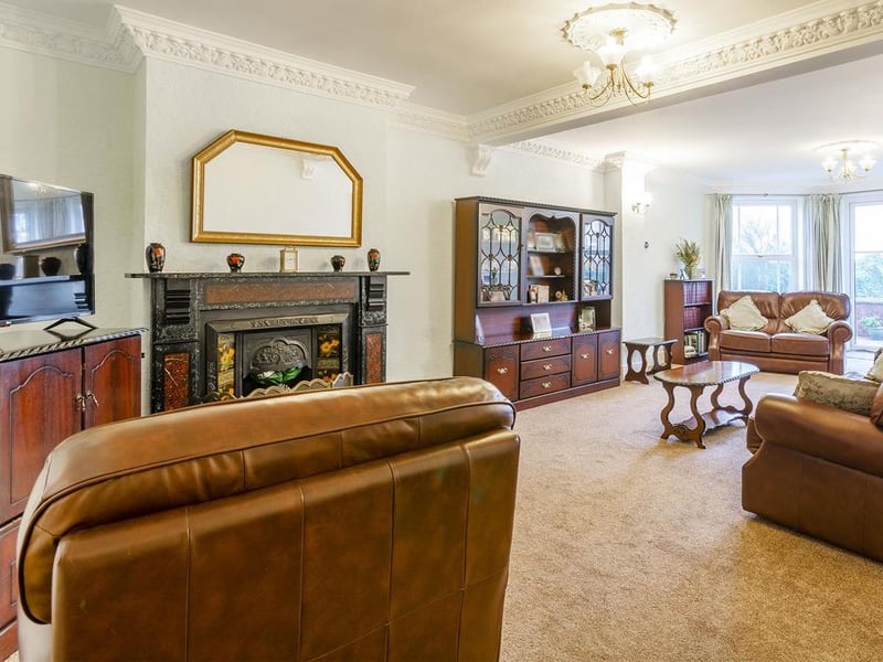 With carpet to flooring, feature fireplace with surround, windows to the rear elevation and double doors leading outside.