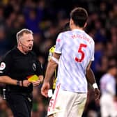Manchester United's Harry Maguire (right) is sent off by referee Jonathan Moss after being shown a second yellow card during the Premier League match at Vicarage Road, Watford.