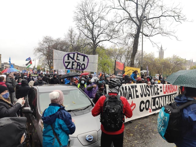 A sign which reads "net zero" being held up high above the crowds of activists.