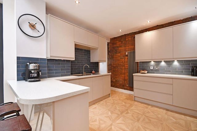 The kitchen contains a range of modern fitted units and is finished with a parquet wood effect floor, an exposed brick wall and stylish tiling. Included with the sale is an integrated oven, an induction hob, extractor, dishwasher, fridge, and freezer.