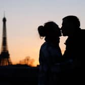 A couple kisses at sunset in front of the Eiffel Tower (L) on the La Concorde bridge over the Seine river in Paris on February 25, 2022. (Photo by Ludovic MARIN / AFP) (Photo by LUDOVIC MARIN/AFP via Getty Images)
