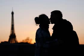 A couple kisses at sunset in front of the Eiffel Tower (L) on the La Concorde bridge over the Seine river in Paris on February 25, 2022. (Photo by Ludovic MARIN / AFP) (Photo by LUDOVIC MARIN/AFP via Getty Images)