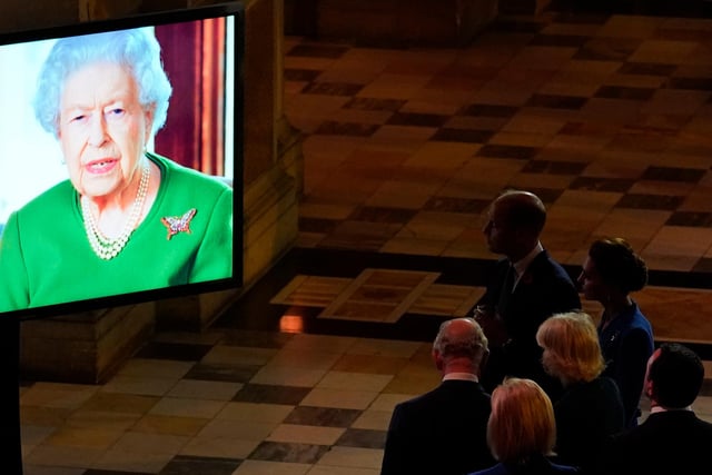 Prince William, Duke of Cambridge and Catherine, Duchess of Cambridge listen to Queen Elizabeth II as she appears on a large screen to make a video message to attendees.